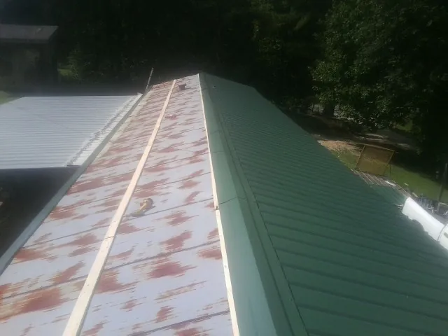 Old rusted panels beside newly installed green metal roofing — Wind Damage Roof Repair by Roofing Brothers in Dekalb