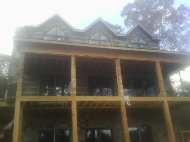 Dormers and porch framing on a large log home under construction — Roof Coating work by our crew in Dekalb