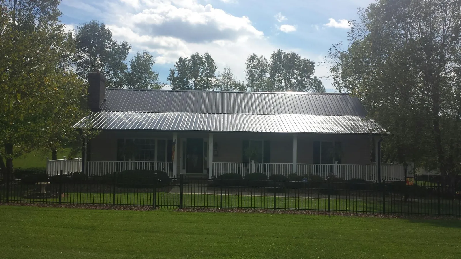 Gray metal roof on a brick ranch with a full width front porch — Gutter Guard Installation work by our crew in Dekalb