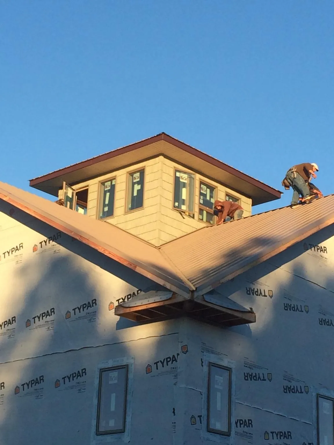 Roofers working around a rooftop cupola on a new metal roof at sunset — Roof Waterproofing in Dekalb by Roofing Brothers